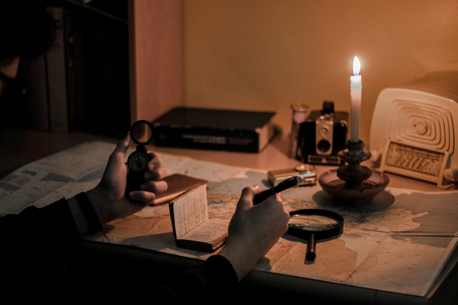 A vintage desk scene with a map, compass, and candlelight, evoking a sense of exploration.