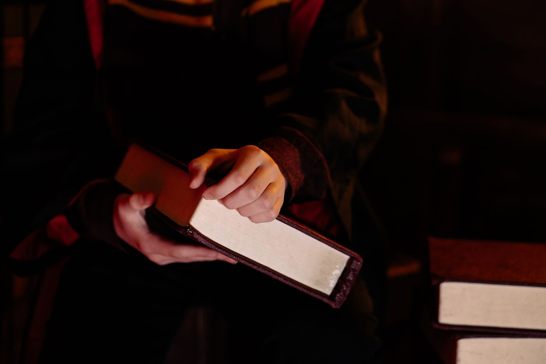 Person holding a magic book in a dark, mysterious setting